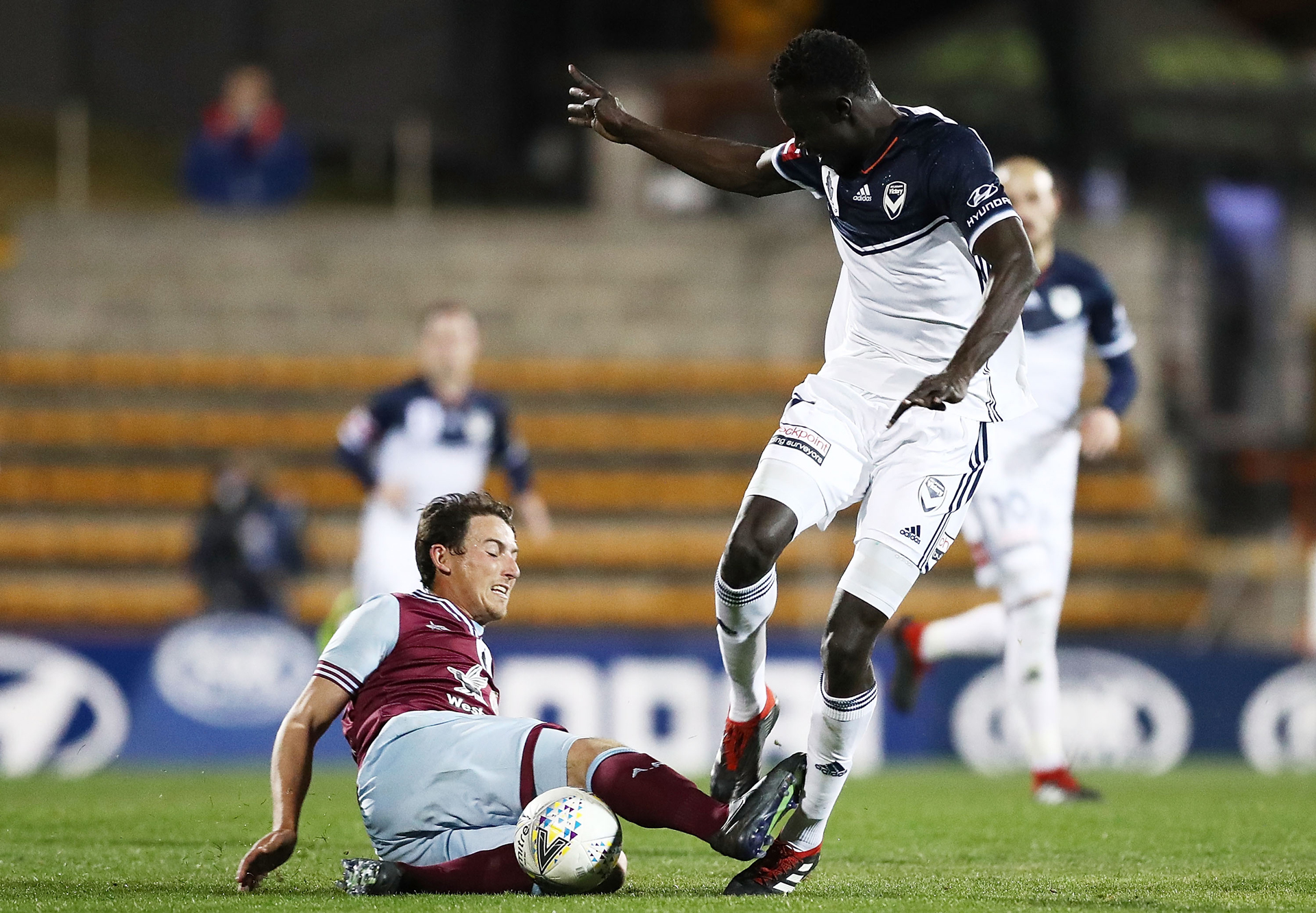 Kenny Athiu of the victory is tackled by Josh Symons of APIA Leichhardt Tigers during the FFA Cup round of 16 match between APIA Leichhardt Tigers FC and Melbourne Victory at Leichhardt Oval on August 21, 2018