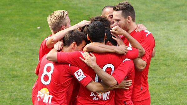 Adelaide United players celebrate scoring against the Mariners.